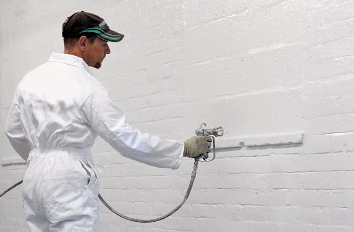 Spray painting brick wall with masonry paint